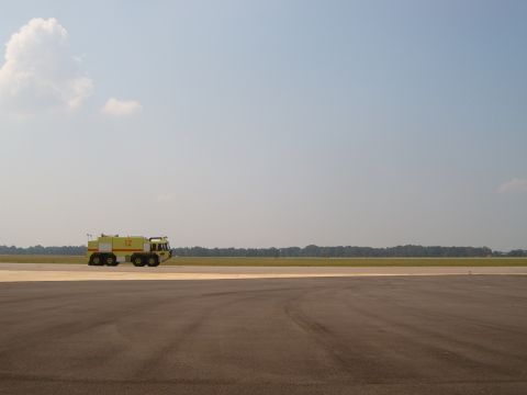 1988 Ford Bronco - A yellow airport fire truck is seen driving on a tarmac under a clear blue sky.