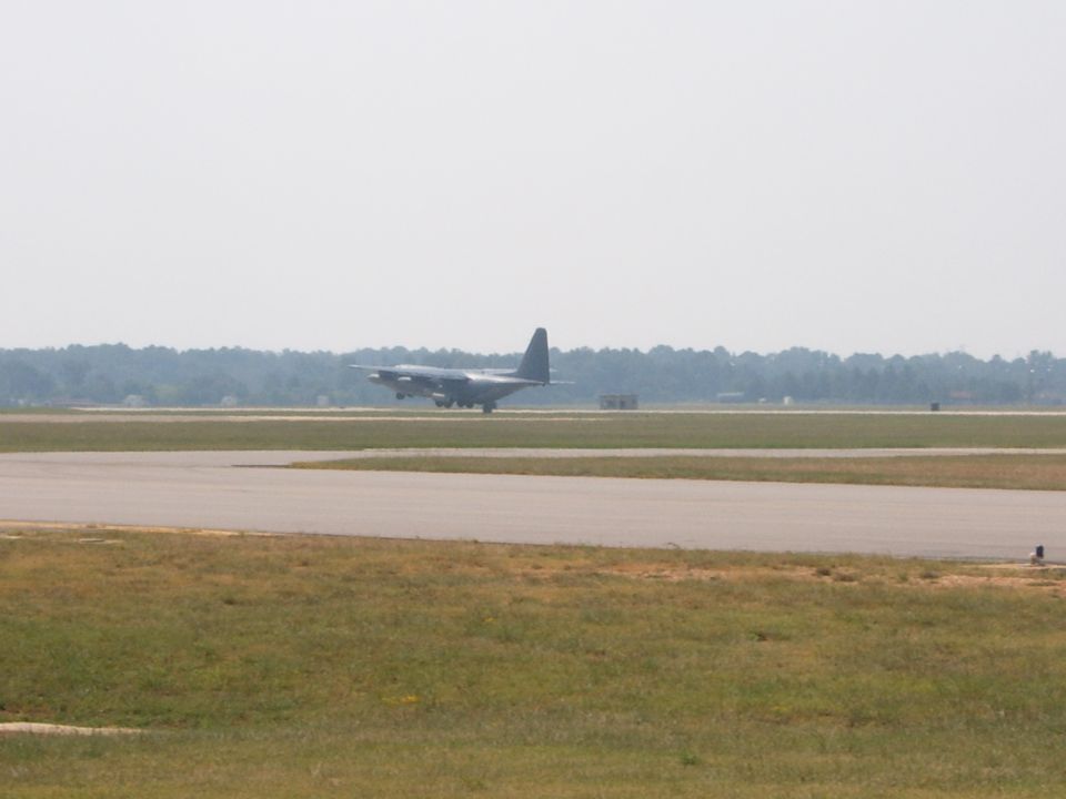 Dark-colored airplane on a runway, viewed from the side