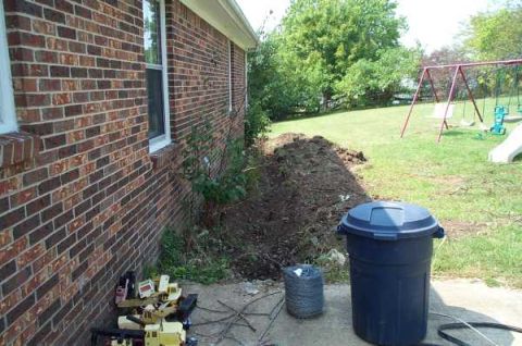 1988 Ford Bronco - A blue trash can and construction debris are visible next to a brick house with a backyard swing set in the background.