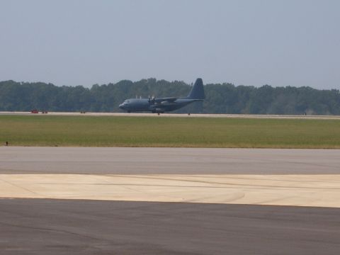 1988 Ford Bronco - A large military transport airplane is on the runway, with a line of trees visible in the distance.