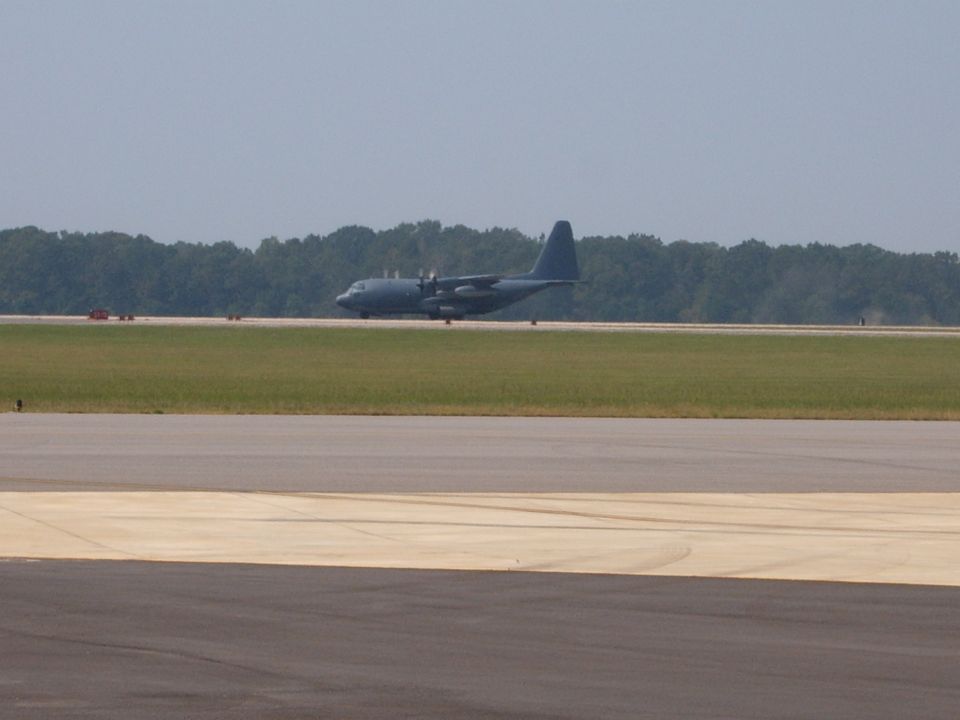 Military transport airplane on a runway with trees in the background