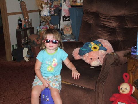 1966 Ford Ranchero - A young girl with sunglasses on sits in a room filled with various decorative items and stuffed animals.