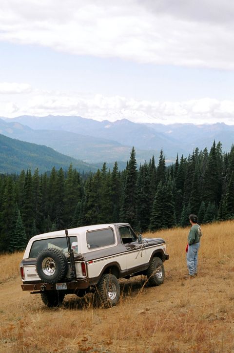 1979 Ford Bronco - 1979 Ford Bronco in a scenic mountain landscape with a person observing the view.
