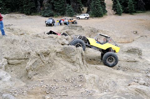 1979 Ford Bronco - Off-road vehicles navigate a challenging rocky course with trees in the background.