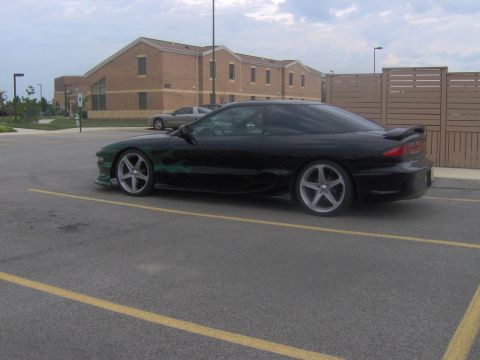 1994 Ford Probe - A black coupe with custom green flame decals is parked in a lot next to a building.