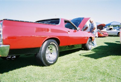 1972 Ford Ranchero - A red 1972 Ford Ranchero is parked on grass with its hood open, alongside other vehicles.