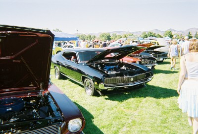 1972 Ford Ranchero - A black coupe, likely from the early 1970s, is displayed with its hood open at an outdoor car show.