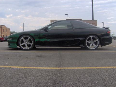 1994 Ford Probe - A black coupe with custom green flame graphics is parked in a lot under a cloudy sky.