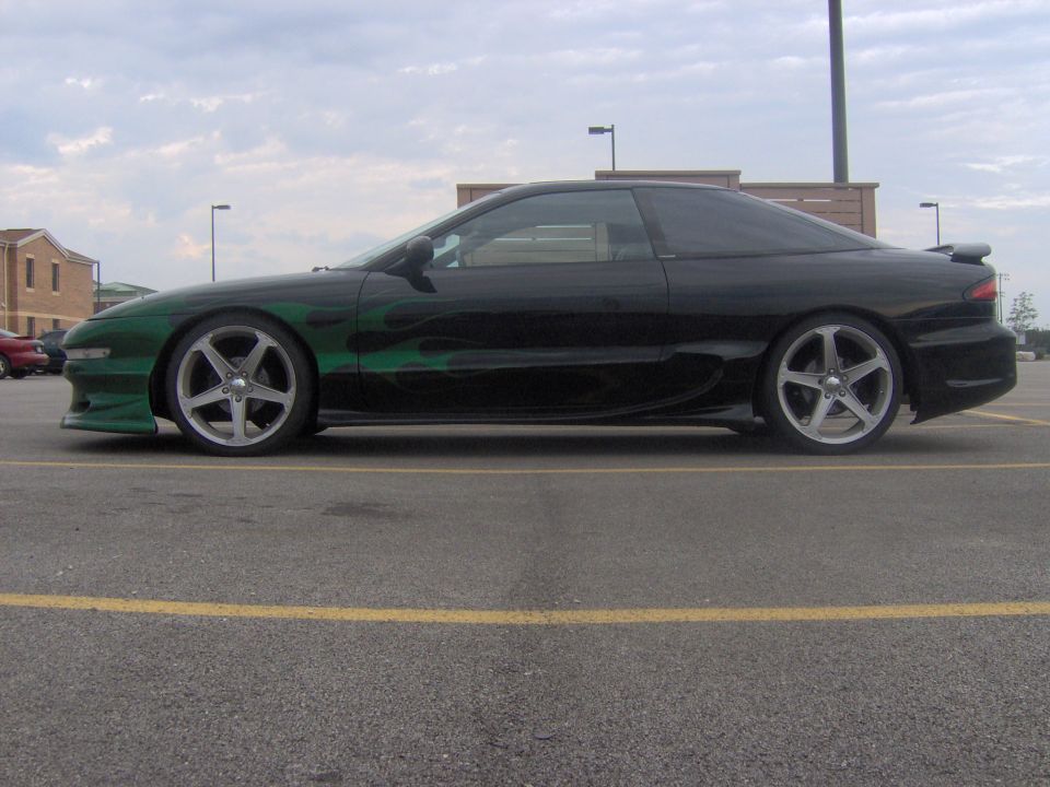 black coupe with green flames on the side, parked in a lot