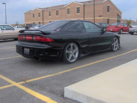 1994 Ford Probe - A black coupe with a spoiler and aftermarket wheels is parked in a lot.