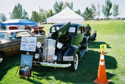 1972 Ford Ranchero - A black sedan is displayed with its hood open at an outdoor event.