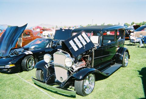 1972 Ford Ranchero - A black hot rod sedan is displayed on a grassy field with other vehicles.