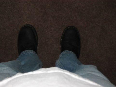 1991 Ford Bronco - A close-up view of feet wearing black shoes and blue jeans against a brown carpeted background.