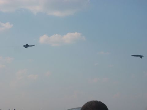 1989 Ford Bronco - Two fighter jets are seen in the sky during an air show, with clouds scattered across the blue expanse.