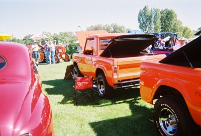 1972 Ford Ranchero - An orange pickup truck with its tailgate open is parked on a grassy field at an outdoor event.