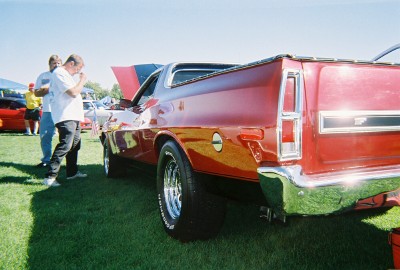 1972 Ford Ranchero - A red 1972 Ford Ranchero is displayed on a grassy field, showing its rear quarter panel and chrome bumper.