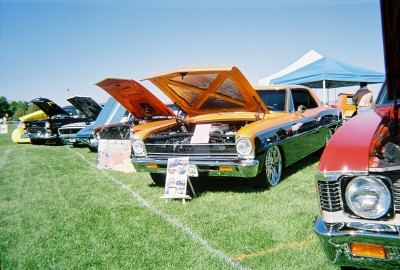 1972 Ford Ranchero - Cars are lined up on a grassy field under a clear blue sky, with some tents in the background.