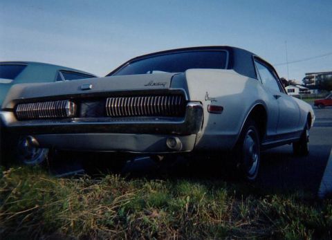1968 Mercury Cougar - The rear of a Mercury Cougar shows its distinctive grille and badging, parked on grass under a blue sky.
