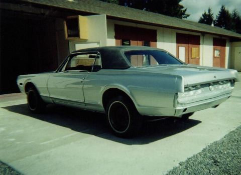 1968 Mercury Cougar - Rear view of a silver 1968 Mercury Cougar coupe with a black vinyl top parked in front of a building.