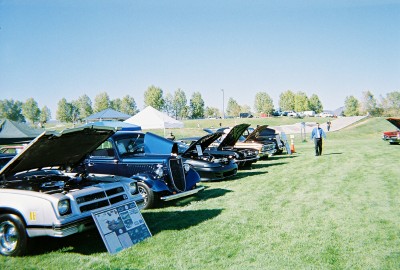 1972 Ford Ranchero - Several vehicles are displayed with their hoods open on a grassy field under a clear blue sky.