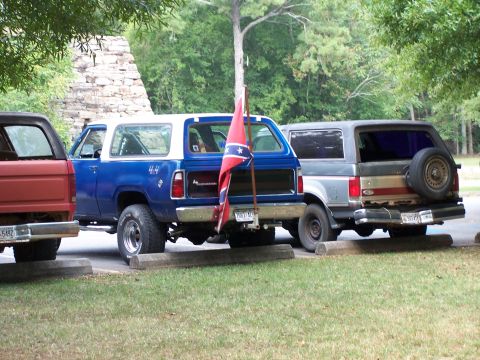 1979 Ford F-150 - Multiple SUVs and a truck are parked in a lot, with one SUV displaying a Confederate flag.