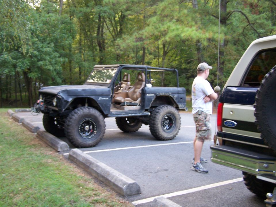 Black Ford Bronco with doors removed, parked next to another truck