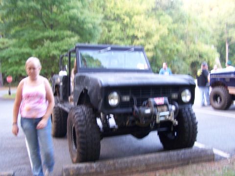 1979 Ford F-150 - A modified SUV with off-road tires and a winch is parked outdoors, with people and another vehicle in the background.