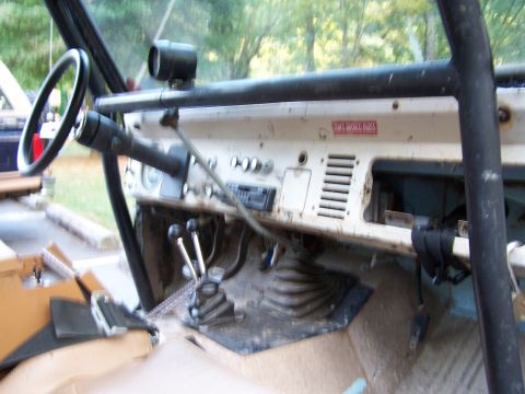 1979 Ford F-150 - Dashboard and interior of a vintage off-road vehicle with a roll cage and a red sticker on the dash.