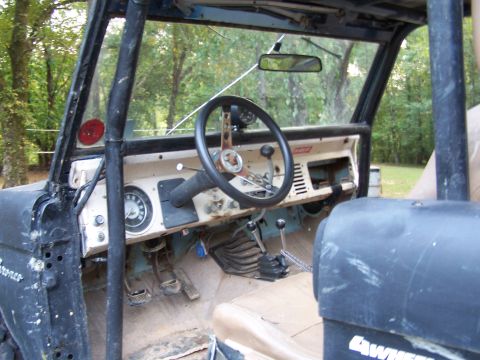 1979 Ford F-150 - The interior of a classic Ford Bronco, a roll cage and aftermarket steering wheel, is shown from the driver's perspective.