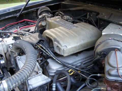 1979 Ford F-150 - The engine bay of a vehicle shows a Ford intake manifold with various hoses and wires.