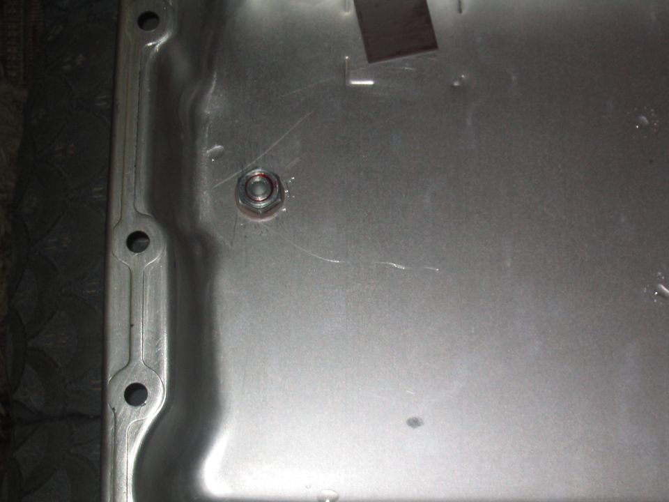 Close-up of a bare sheet-metal panel underside with a single nut and weld marks
