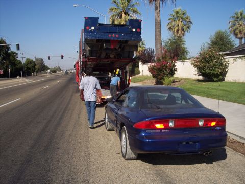 1995 Ford Probe - A blue 1995 Ford Probe is backed off a car carrier on a sunny day.