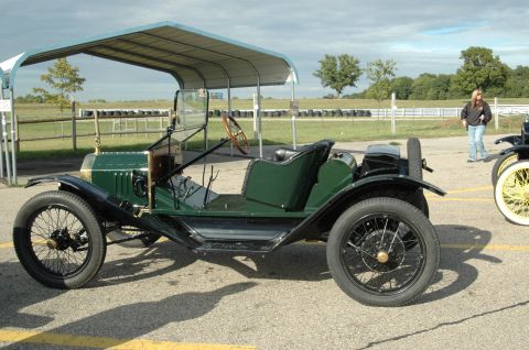 2000 Ford Mustang - A vintage green automobile with a wooden steering wheel is seen from the side.