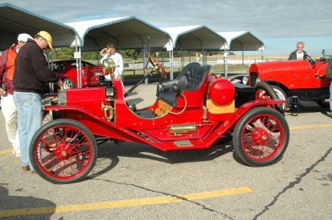 2000 Ford Mustang - This vintage red automobile features a distinctive open-air design with spoked wheels and a black leather seat.