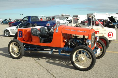 2000 Ford Mustang - An orange 1928 Ford Speedster is parked next to a white GT Racing Team car.