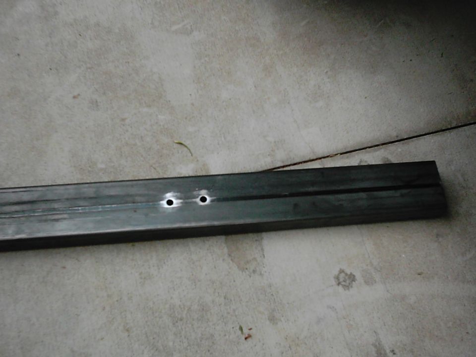 Metal bar with two drilled holes on concrete floor