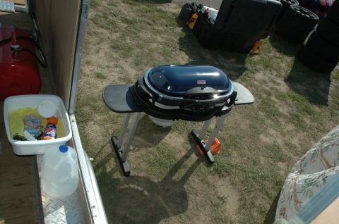 2000 Ford Mustang - Outdoor scene with a portable grill, air tank, and wash bin inside a trailer.