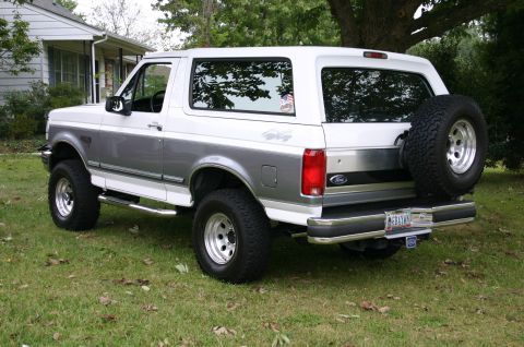 1994 Ford Bronco - This lifted Ford Bronco is parked on a grassy lawn in front of a house.
