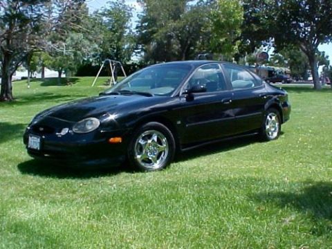 1997 Ford Expedition - A black sedan is parked on a grassy lawn with trees and a playground visible in the background.