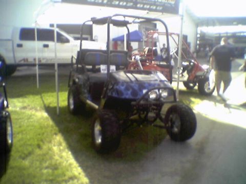 2005 BMW 3 Series - Customized golf cart with flame graphics parked outdoors next to a pickup truck.