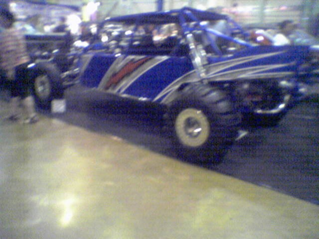Blue dune buggy with silver and red stripes, large tires, and roll cage