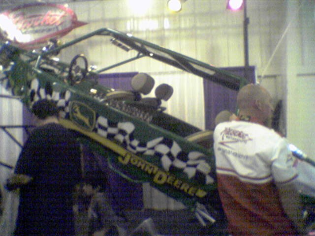 Green and yellow John Deere vehicle with checkered flag graphics, viewed from the side