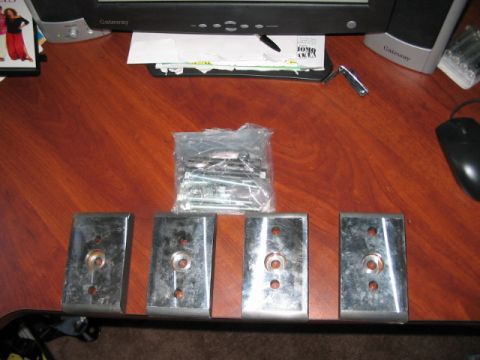 1991 Ford Bronco - Four metal plates and a bag of bolts are laid out on a desk next to a computer monitor.