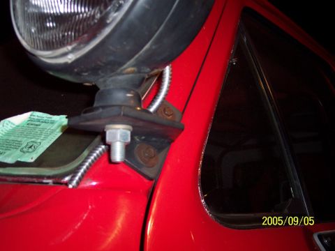 1985 Ford Bronco - Close-up of a red vehicle's fender showing a spotlight mount and a registration sticker.