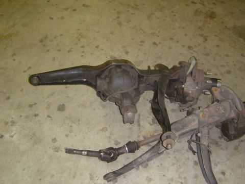 1993 Ford Bronco - A disassembled vehicle axle assembly lies on a concrete surface, showing its various mechanical components.