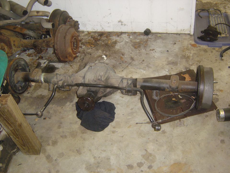 Complete solid front axle with differential, tie rod and hub assembly on a garage floor