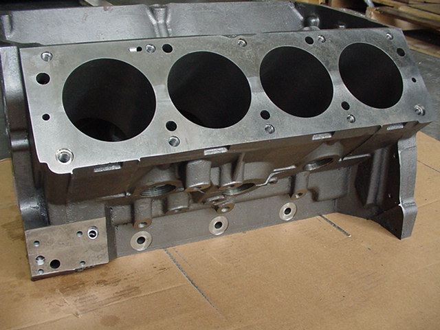 Gray metal engine block with four cylinder bores visible on the top surface
