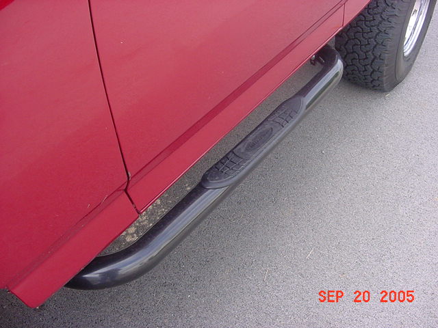 red vehicle side, black nerf bars, tire visible