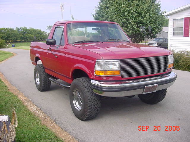 Lifted red Ford Bronco, top removed, billet grille, in driveway