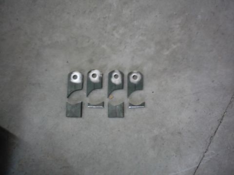 1978 Ford Bronco - Four metal brackets with holes are shown on a concrete floor.